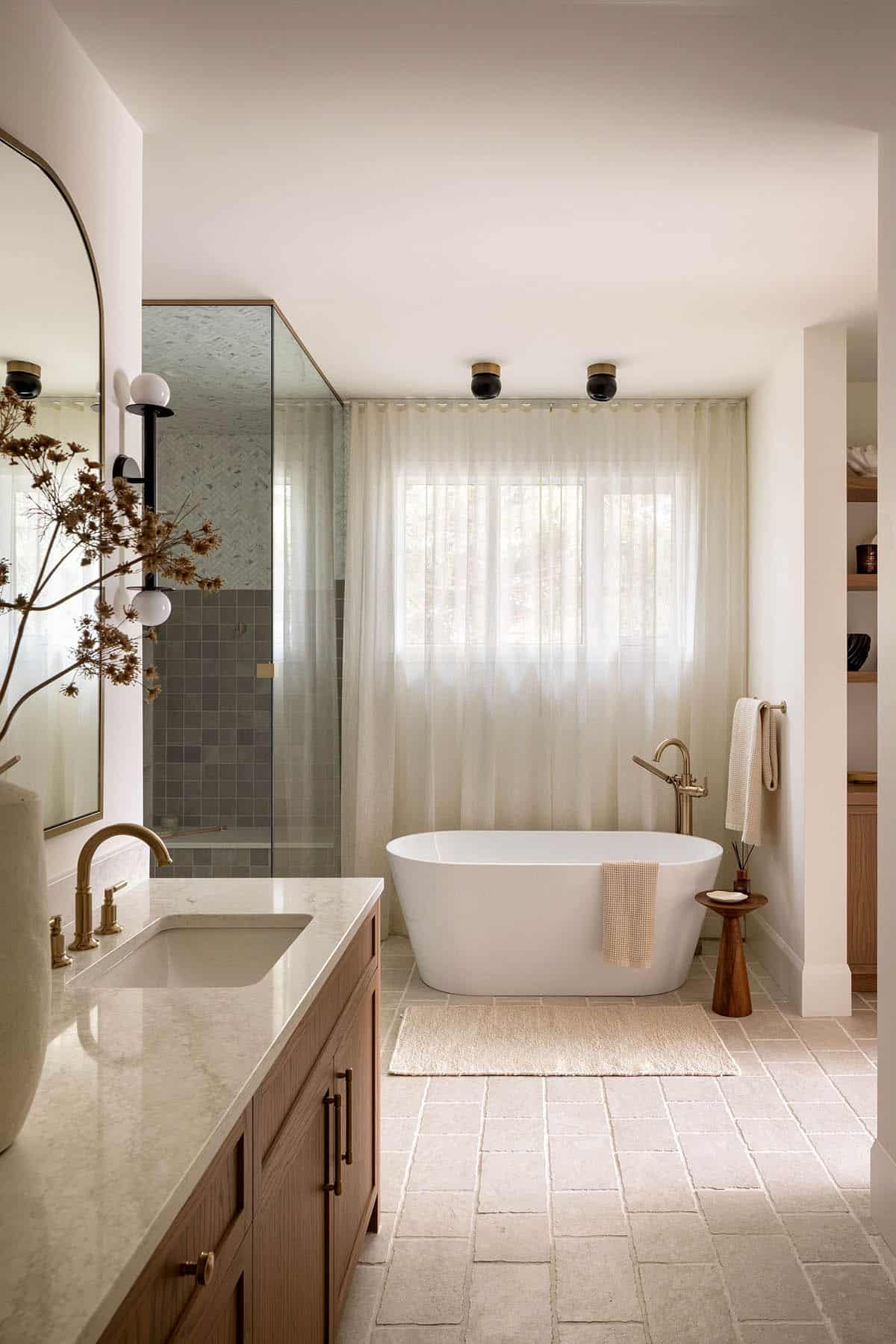 Primary bathroom with freestanding tub, sheer curtains, and wood vanity