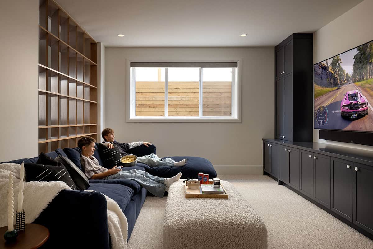 Media room with navy sectional sofa, boys playing video games, and dark built-in TV cabinetry