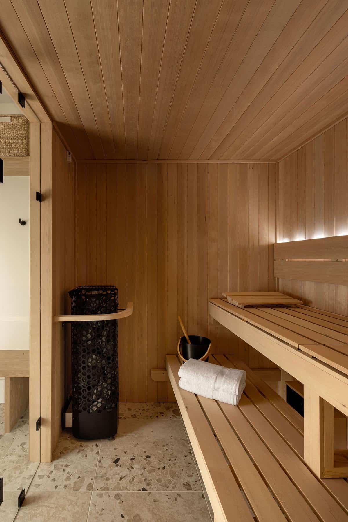 Cedar-lined home sauna with wooden benches and stone heater