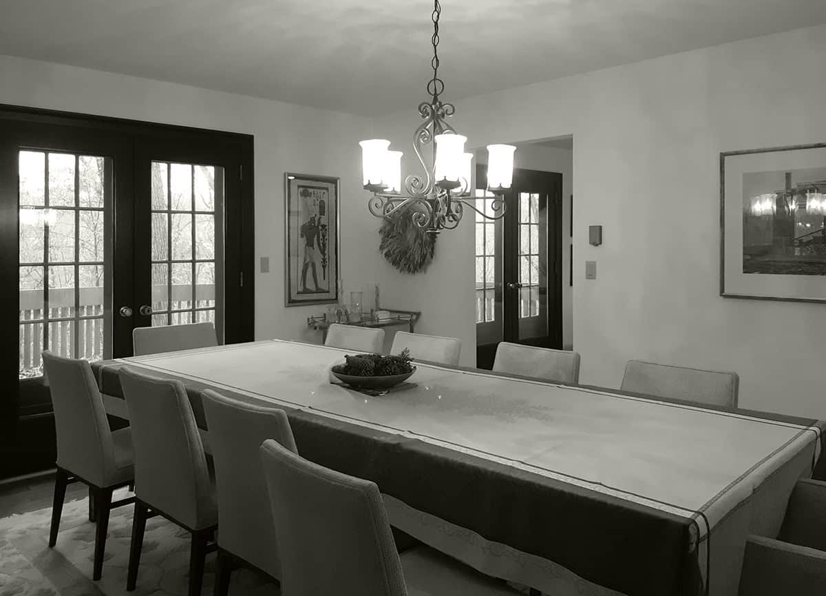 Original dining room with wooden table and iron chandelier before renovation