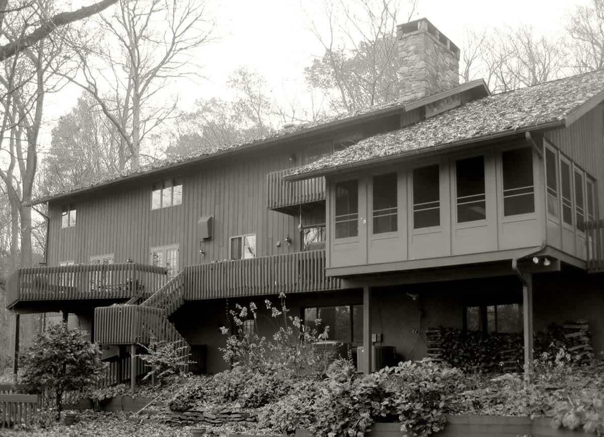 Original rear exterior with wood deck and covered sunroom before renovation