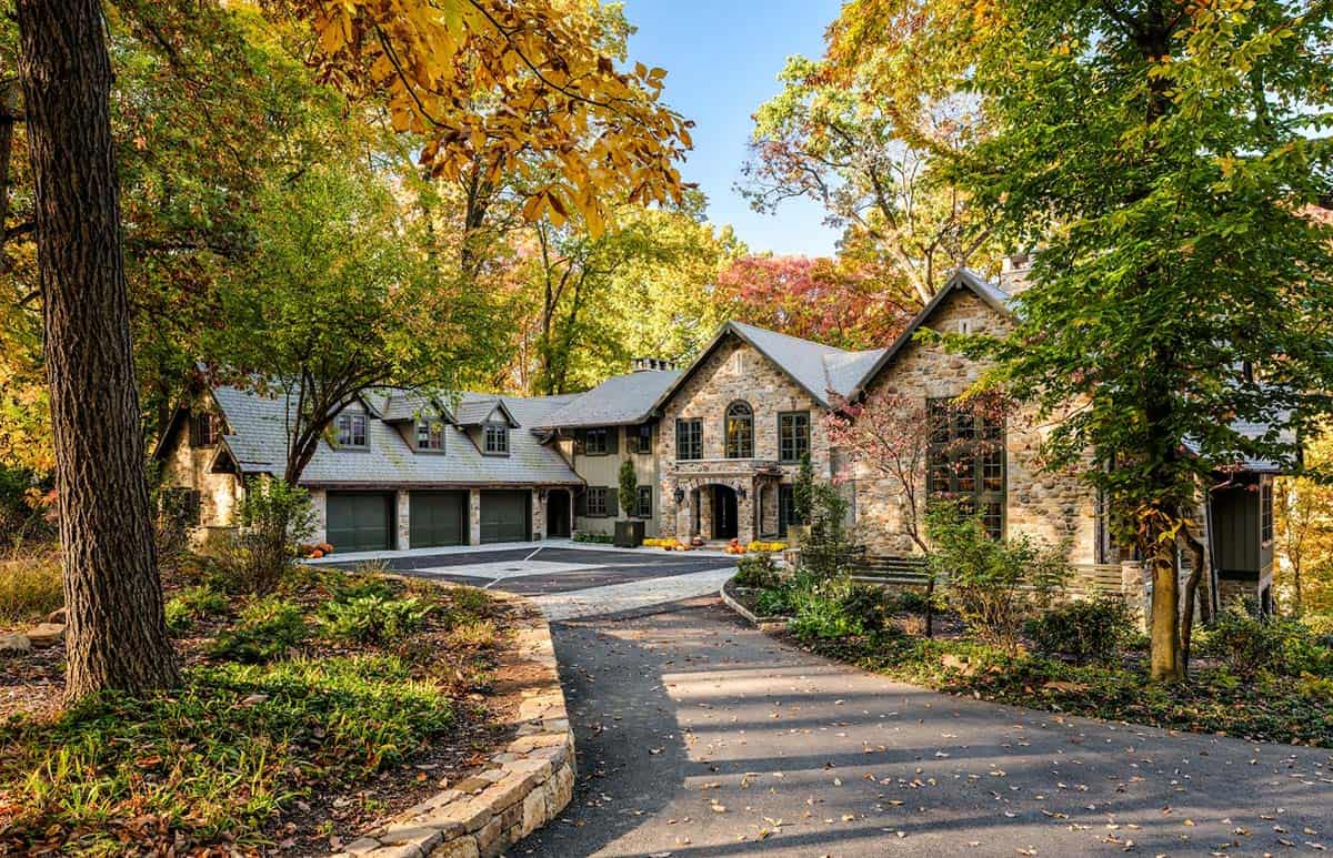 Stone Tudor-style home nestled among trees in autumn foliage