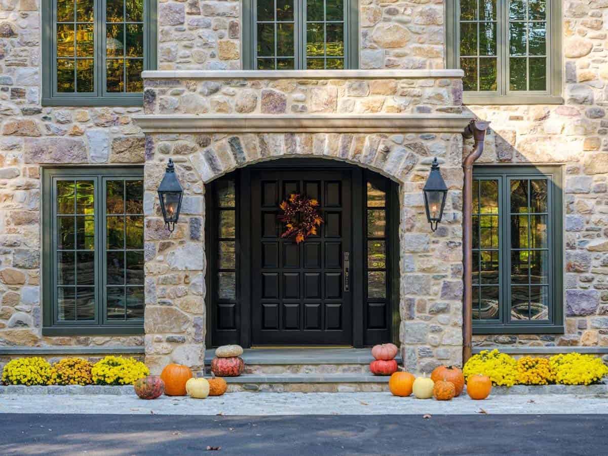 Black front door flanked by lantern sconces and pumpkins