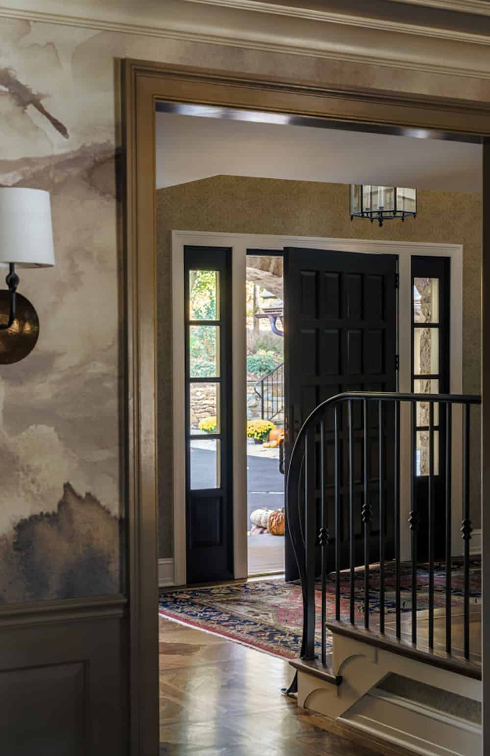 Foyer view through black front door toward autumn garden