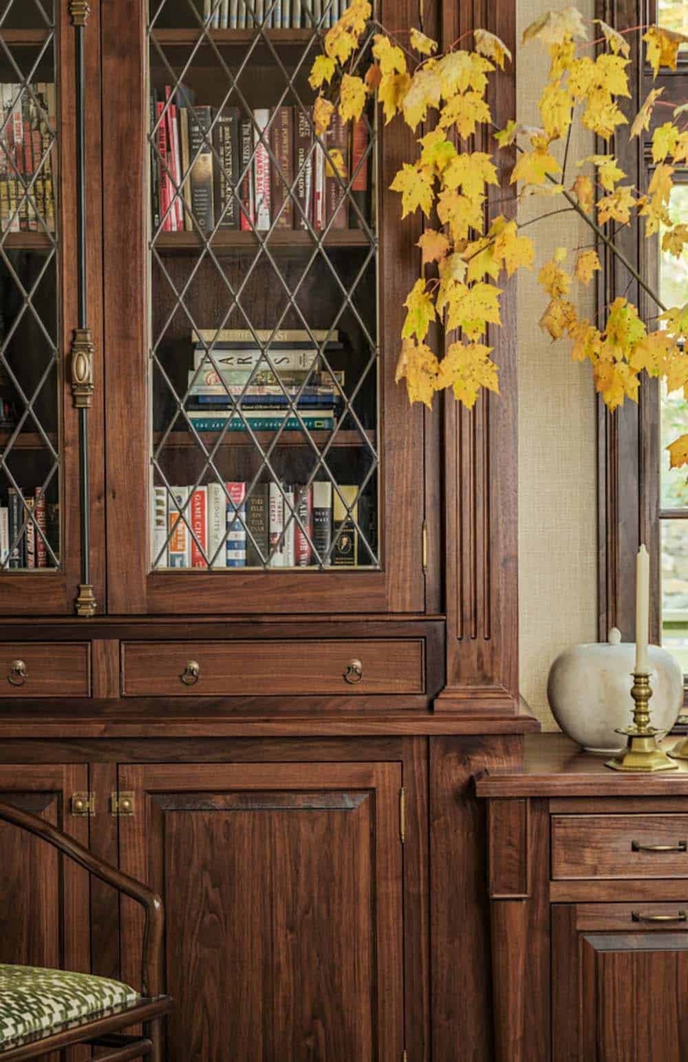 Leaded glass bookcase doors filled with books near fall branches