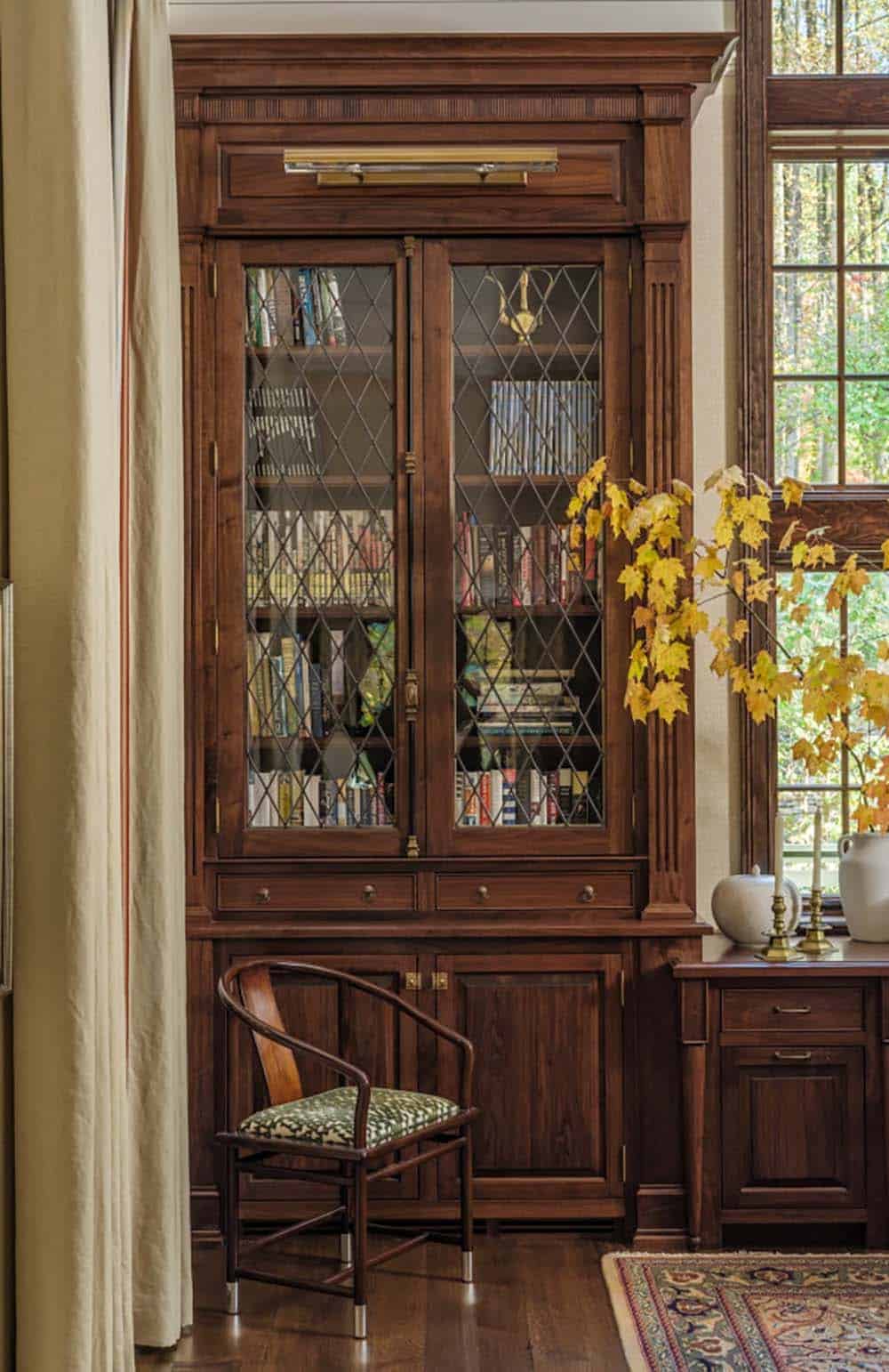 Walnut built-in bookcase with leaded glass doors and reading chair
