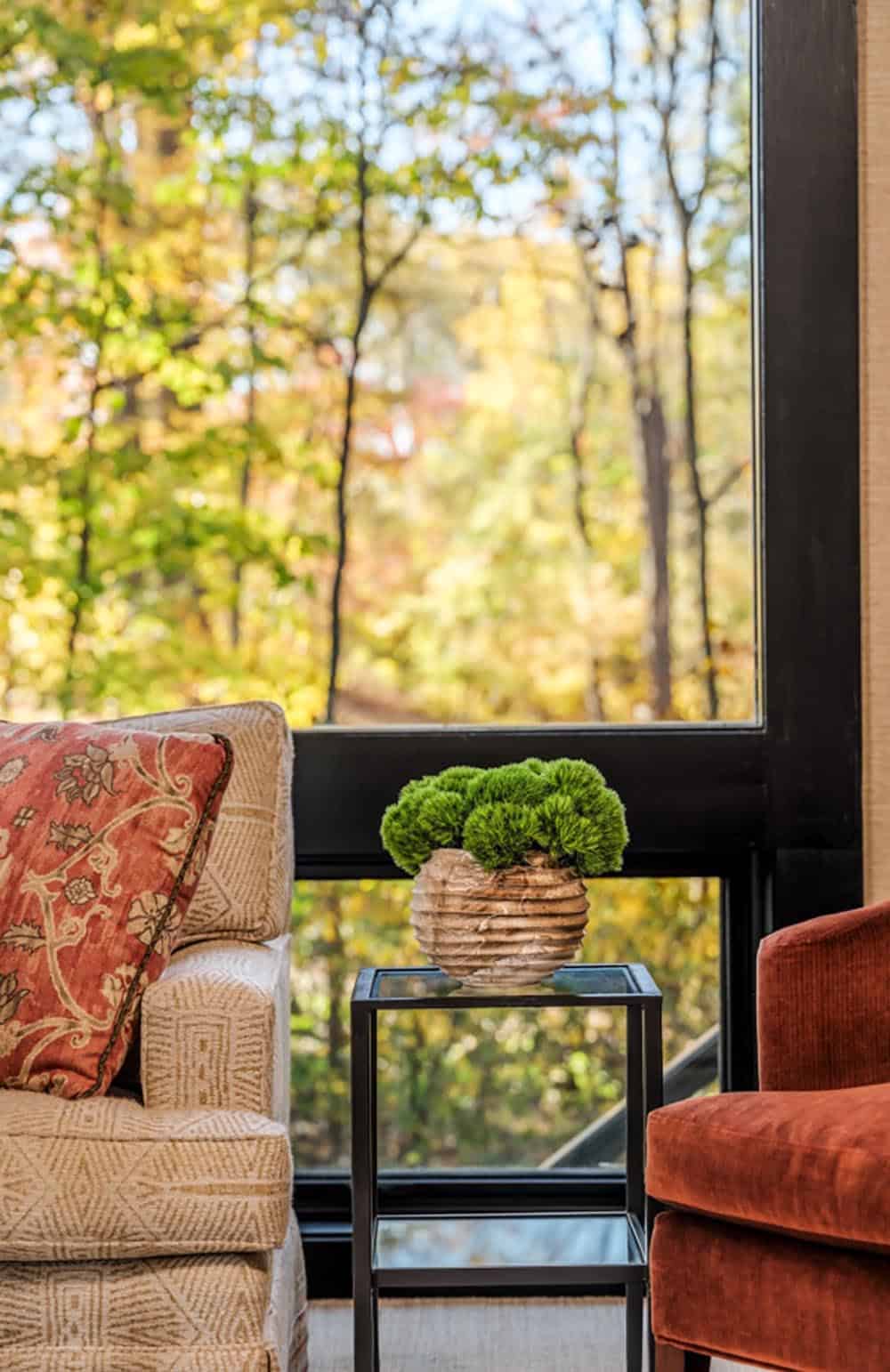 Moss topiary on glass side table beside floor-to-ceiling windows