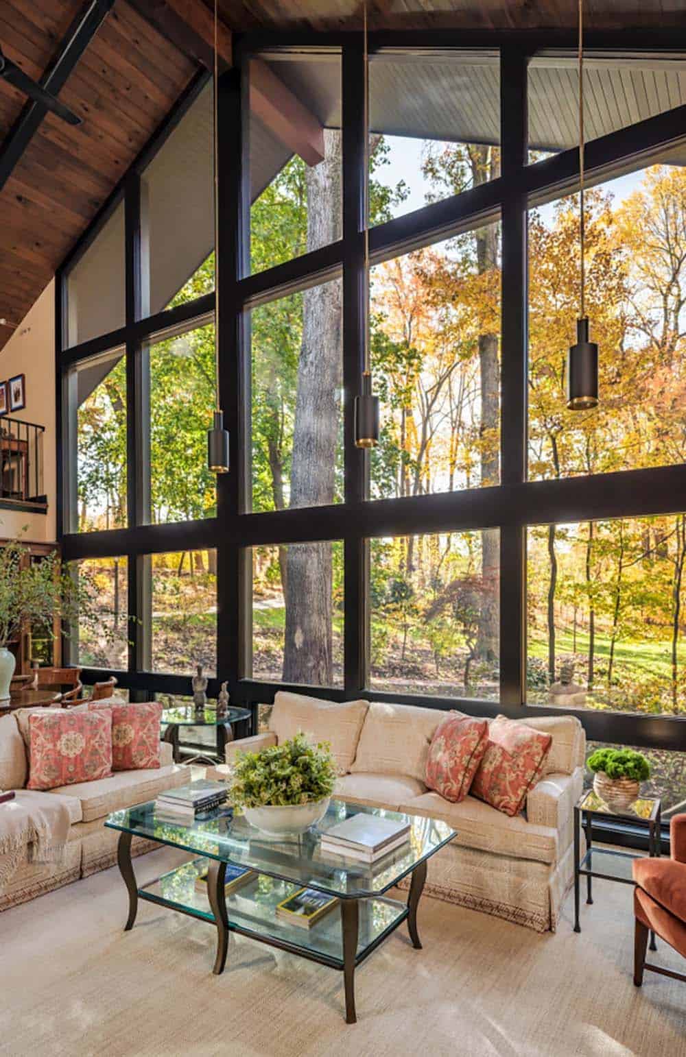 Vaulted sunroom with dramatic glass wall overlooking fall trees