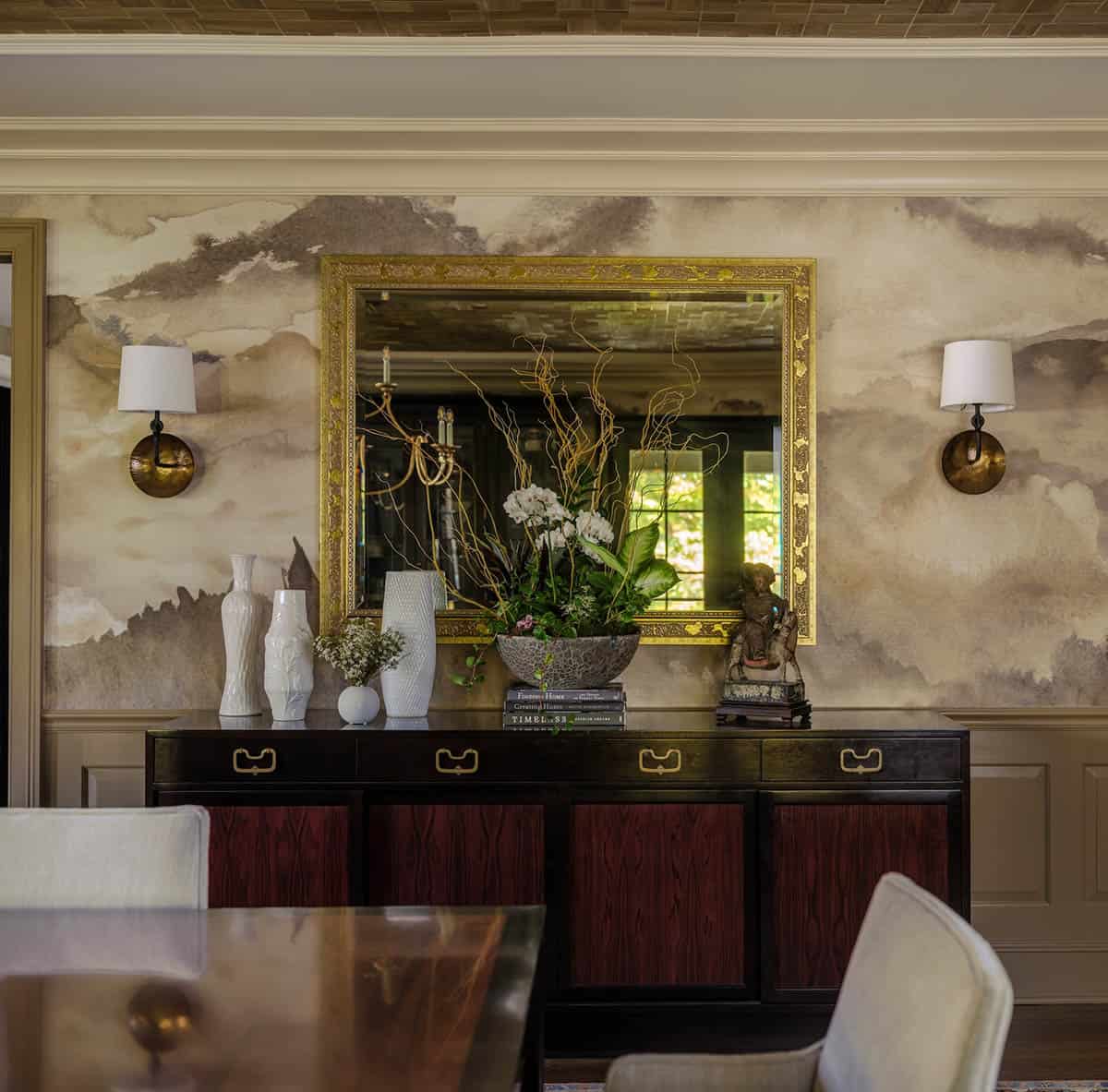 Sideboard vignette with gilded mirror and white ceramic vases