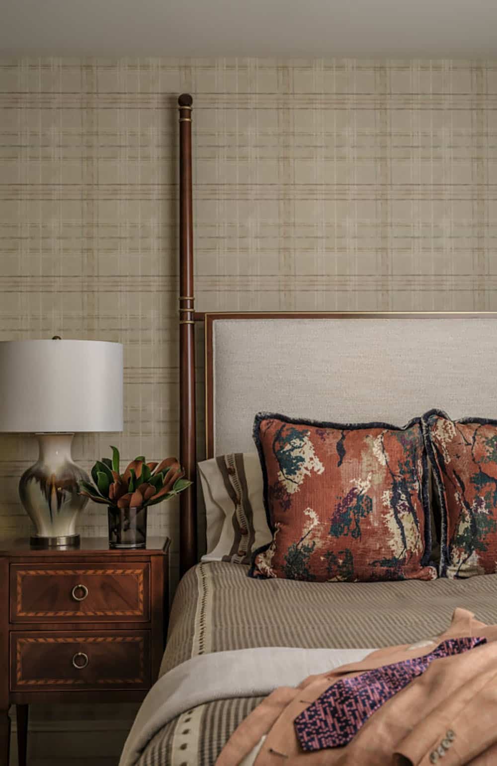 Four poster bed detail with plaid wallpaper and printed pillows