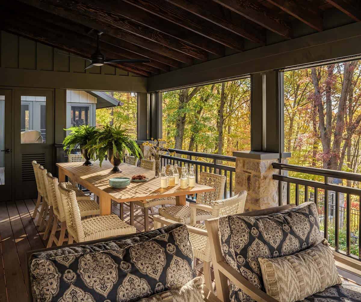 Screened porch dining table set for gathering among fall trees