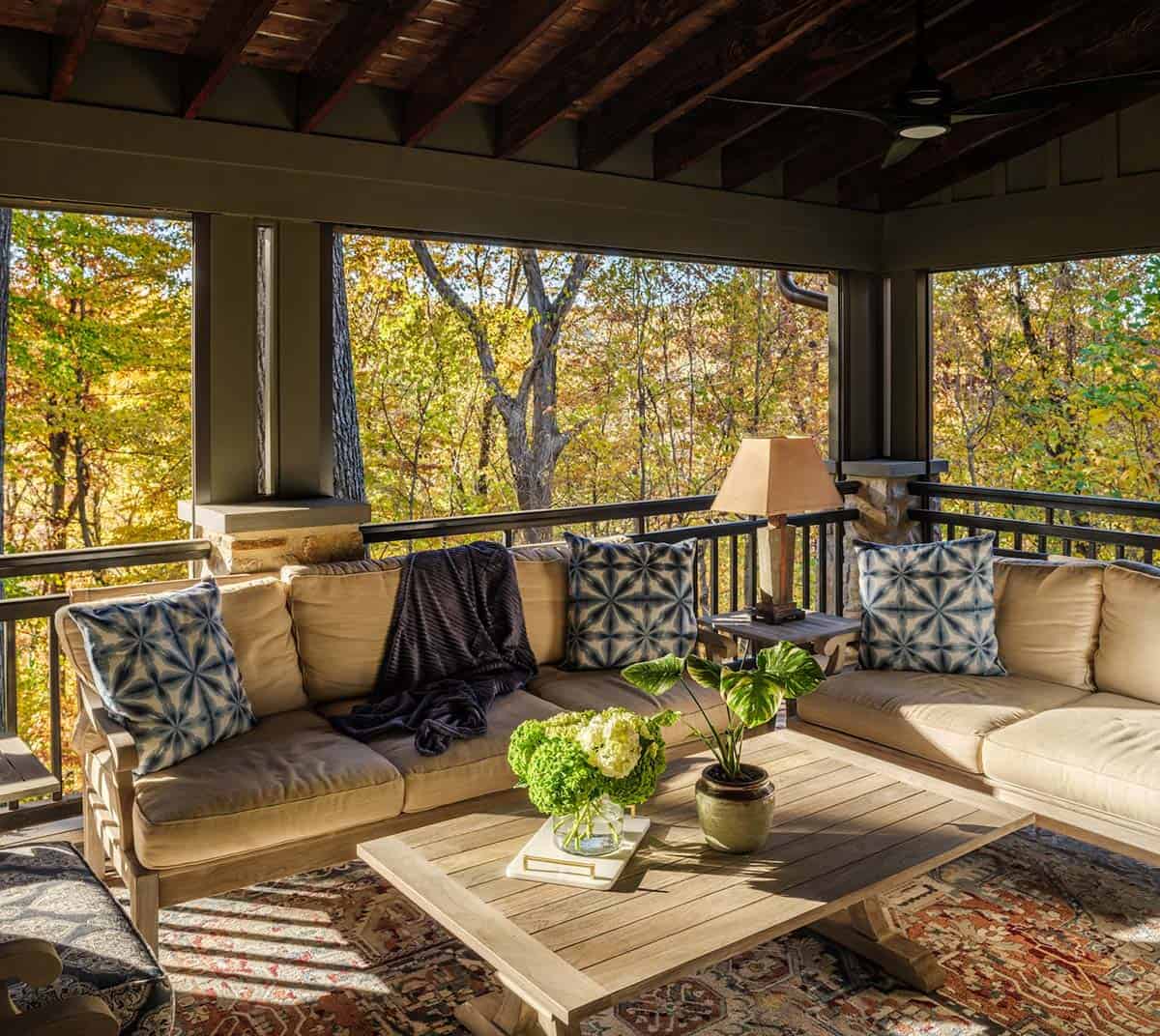 Screened porch sofa with indigo pillows overlooking autumn woods