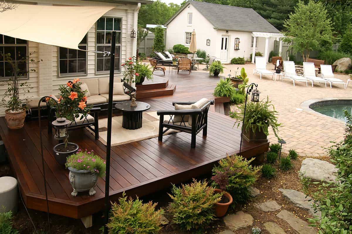 Rich brown Ipe hardwood deck with lounge seating, potted plants, and pool patio view