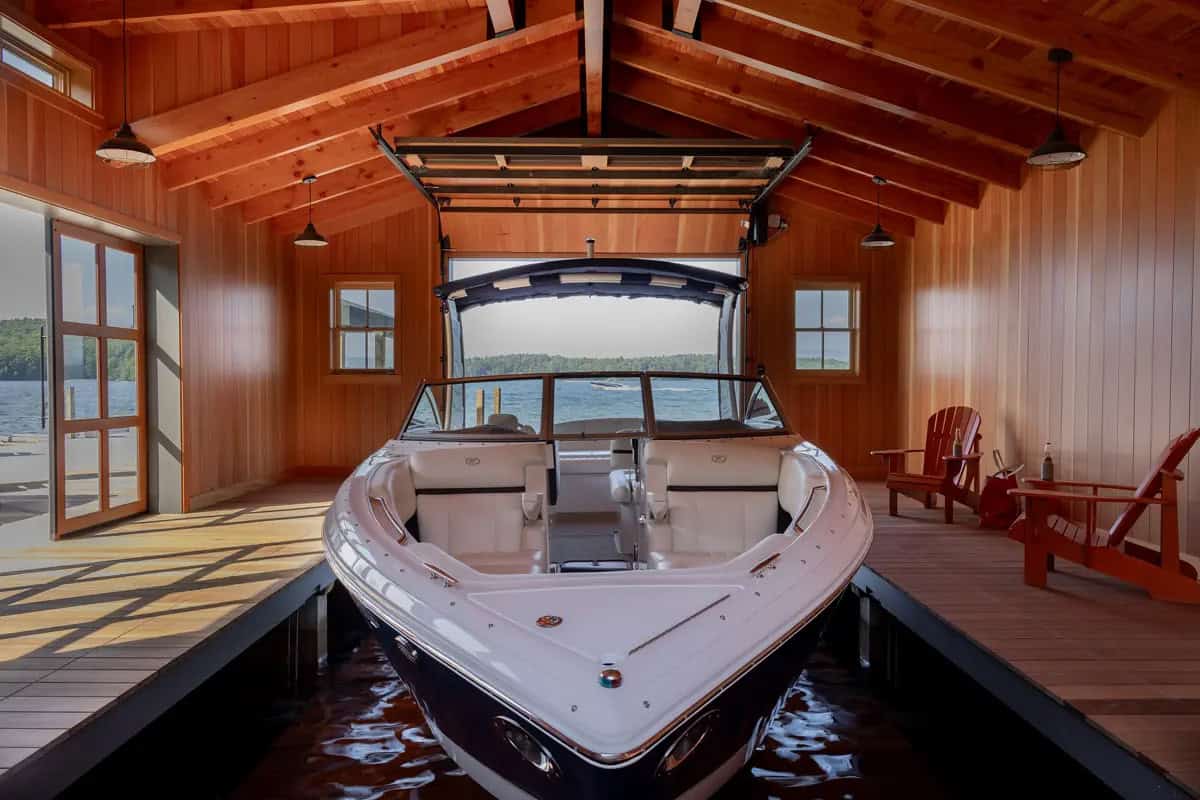 Boat docked inside boathouse with cedar plank ceiling and lake view