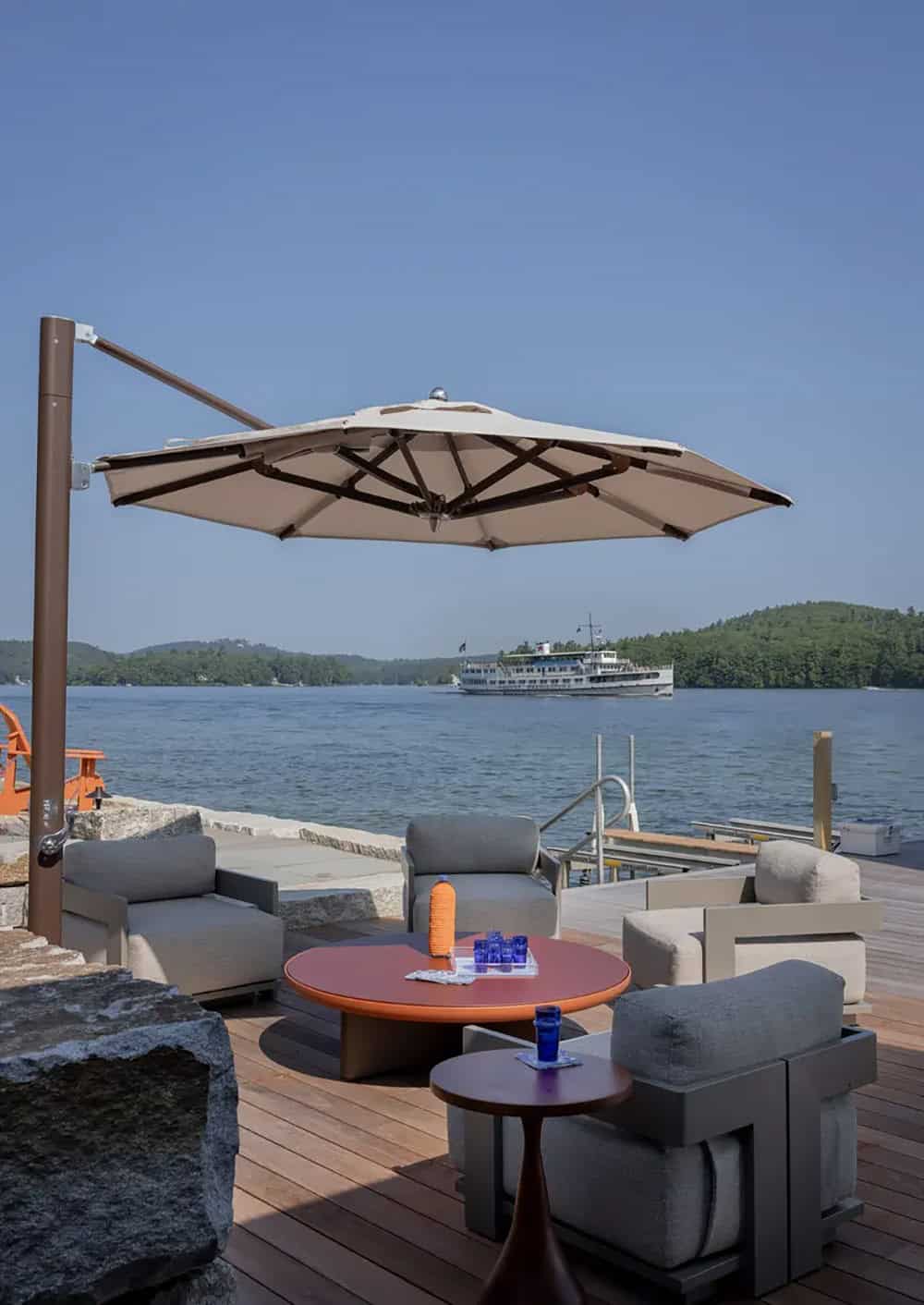 Cantilever umbrella over lounge chairs with lake and tour boat view