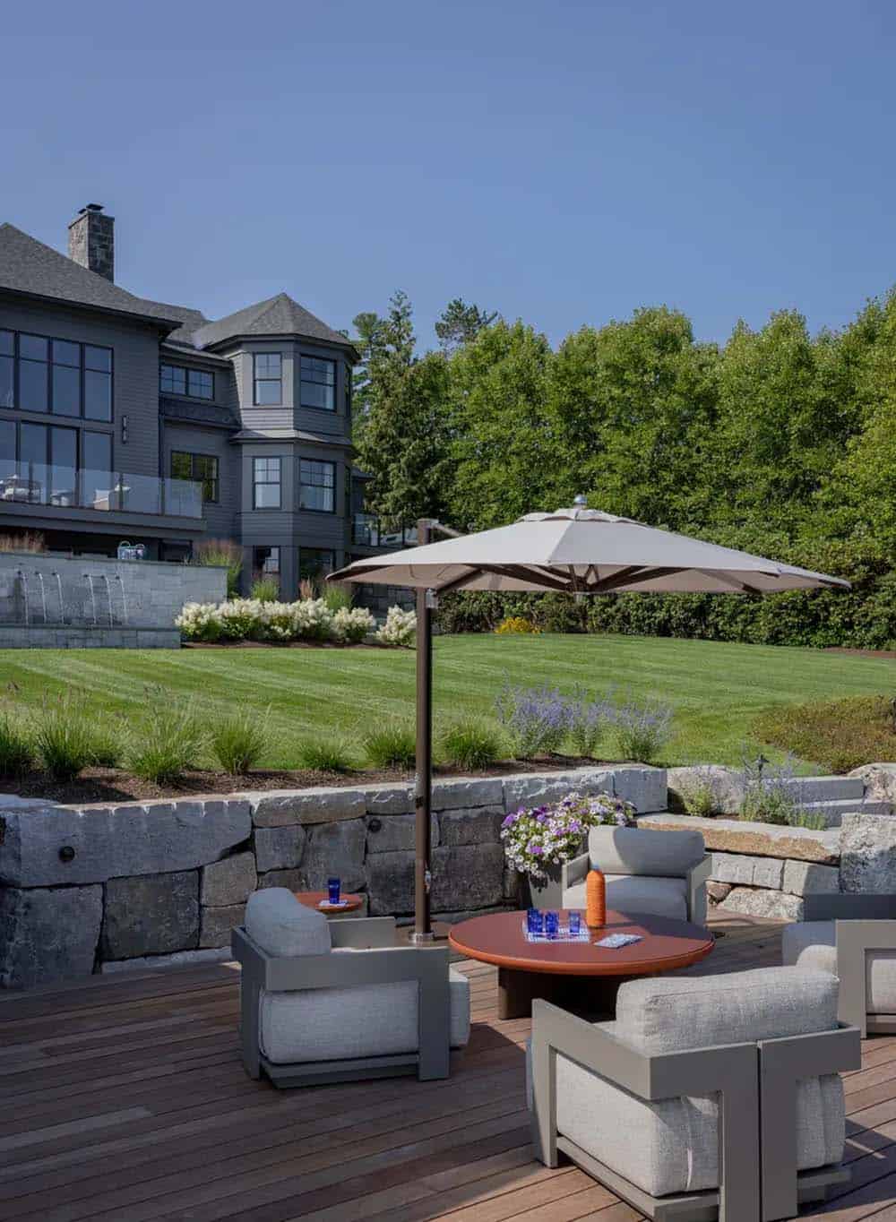 Outdoor lounge seating on deck overlooking sloped lawn and house