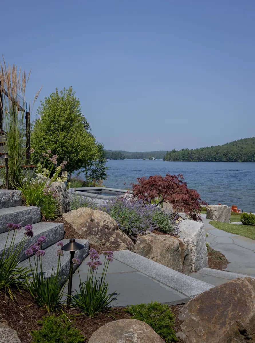 Stone patio steps leading down to the lake with Japanese maple