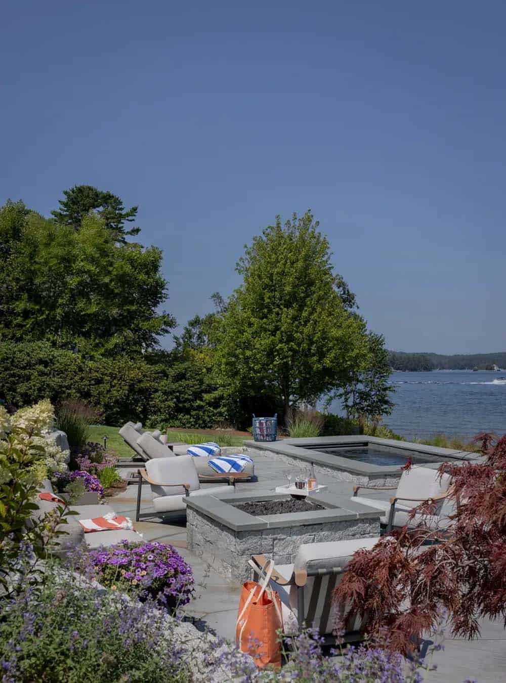 Fire pit and lounge chairs on a stone patio by the water