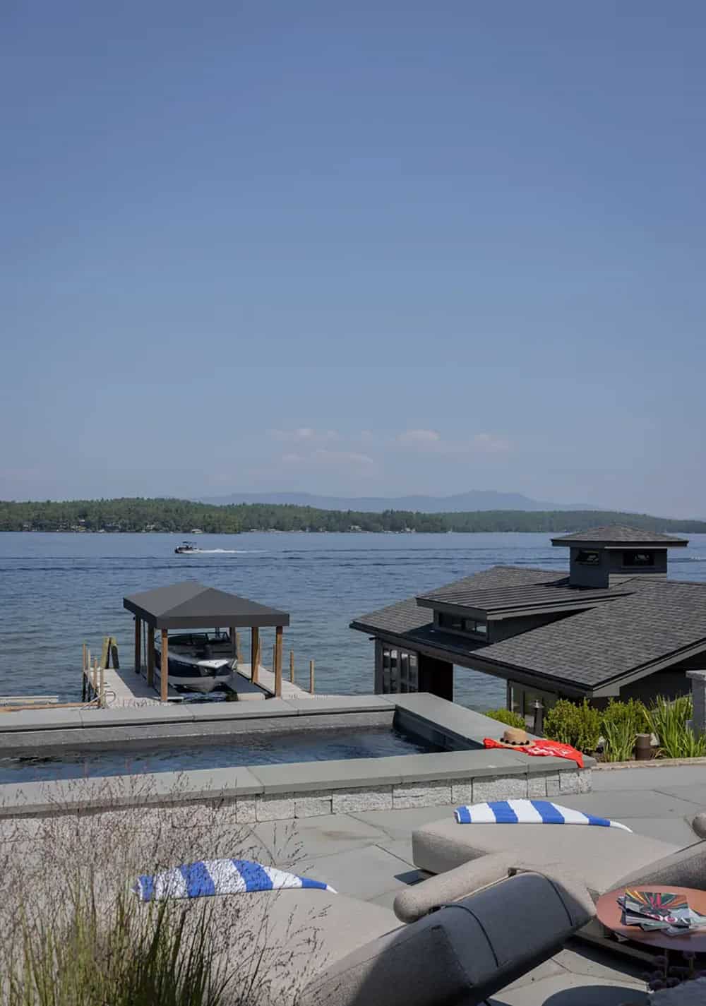 Fire pit and lounge chairs on a stone patio by the water