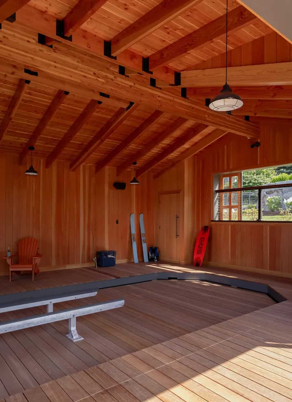 Cedar-lined boathouse interior with boat lift and water sports gear