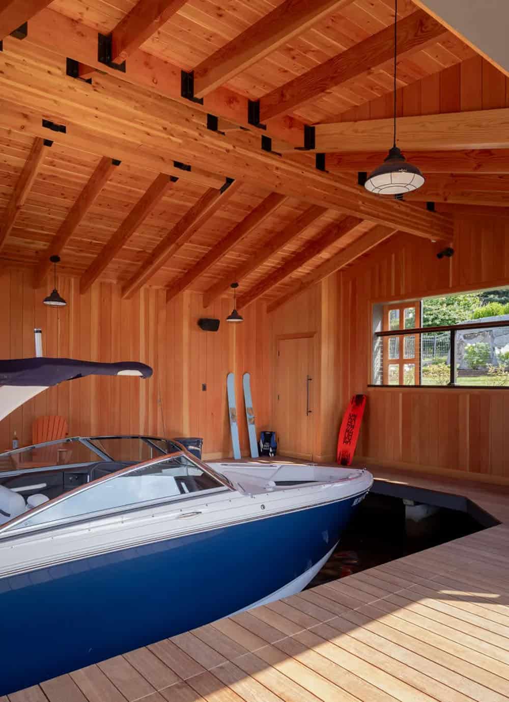 Blue and white boat parked inside a cedar-paneled boathouse
