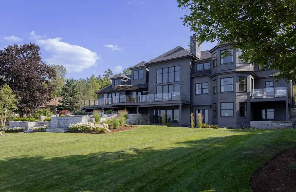 Rear view of gray shingle-style home framed by mature trees