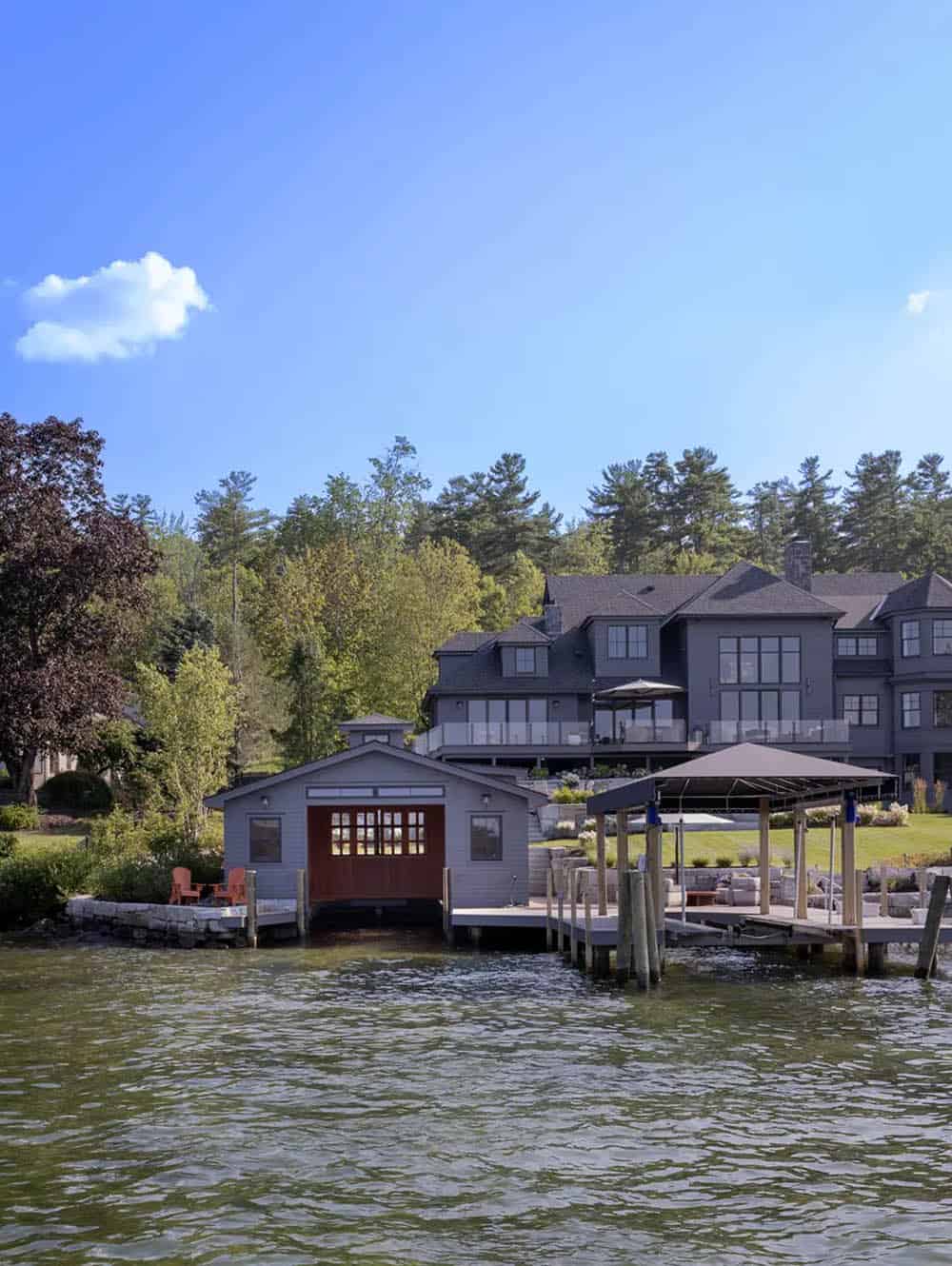 Waterfront view of the boathouse and home framed by tall pines