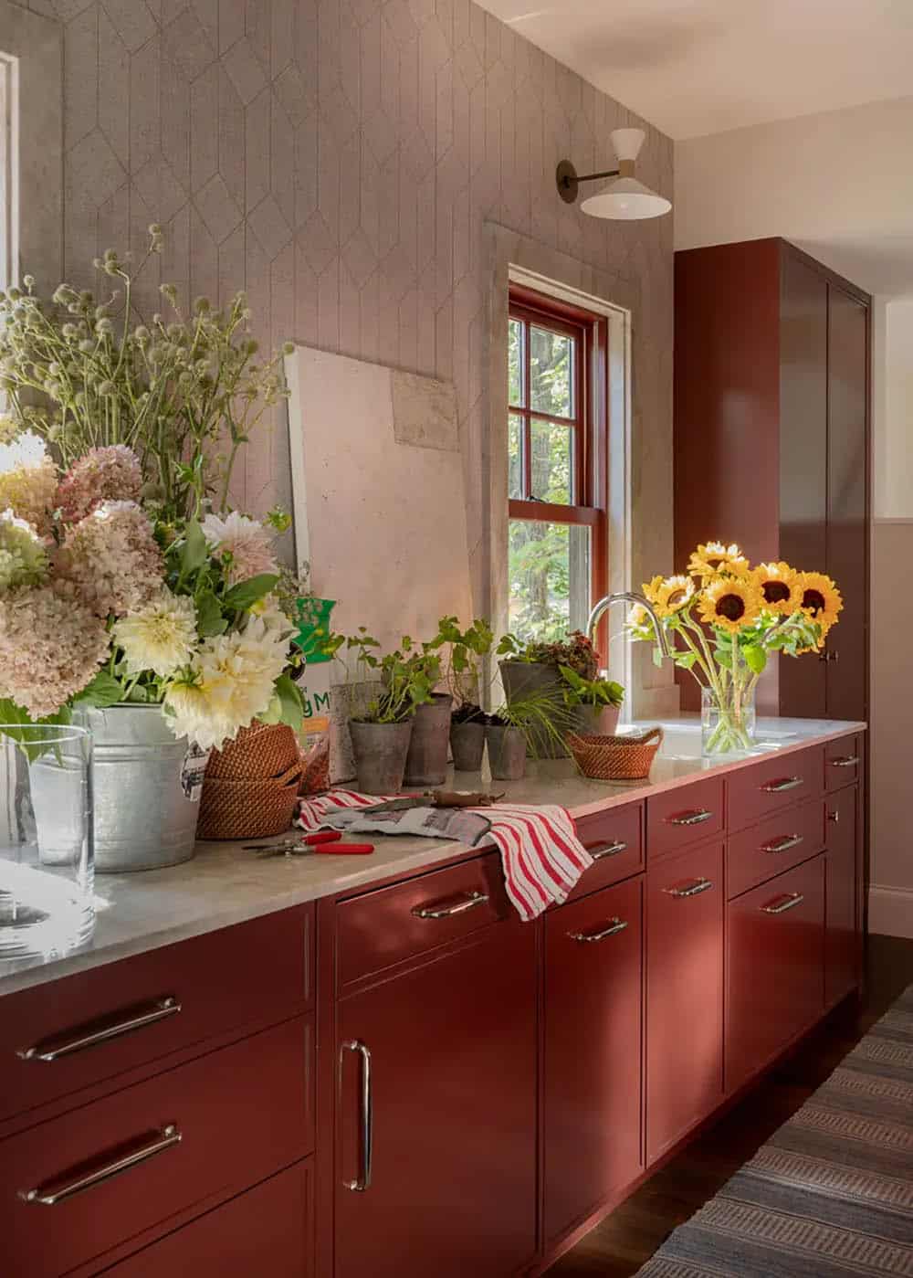 Red kitchen cabinetry with sunflowers and fresh flowers on the counter