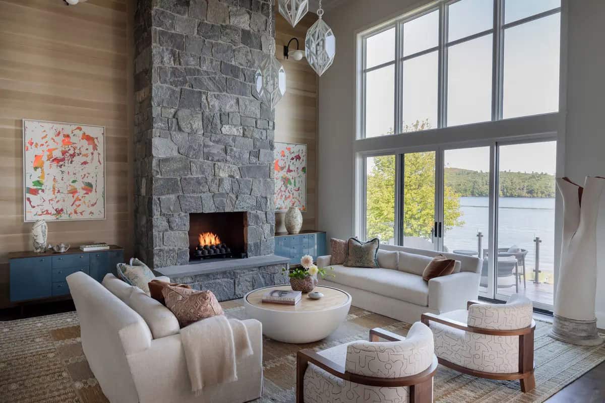 Great room with stone fireplace, white sofas, and lake-view windows
