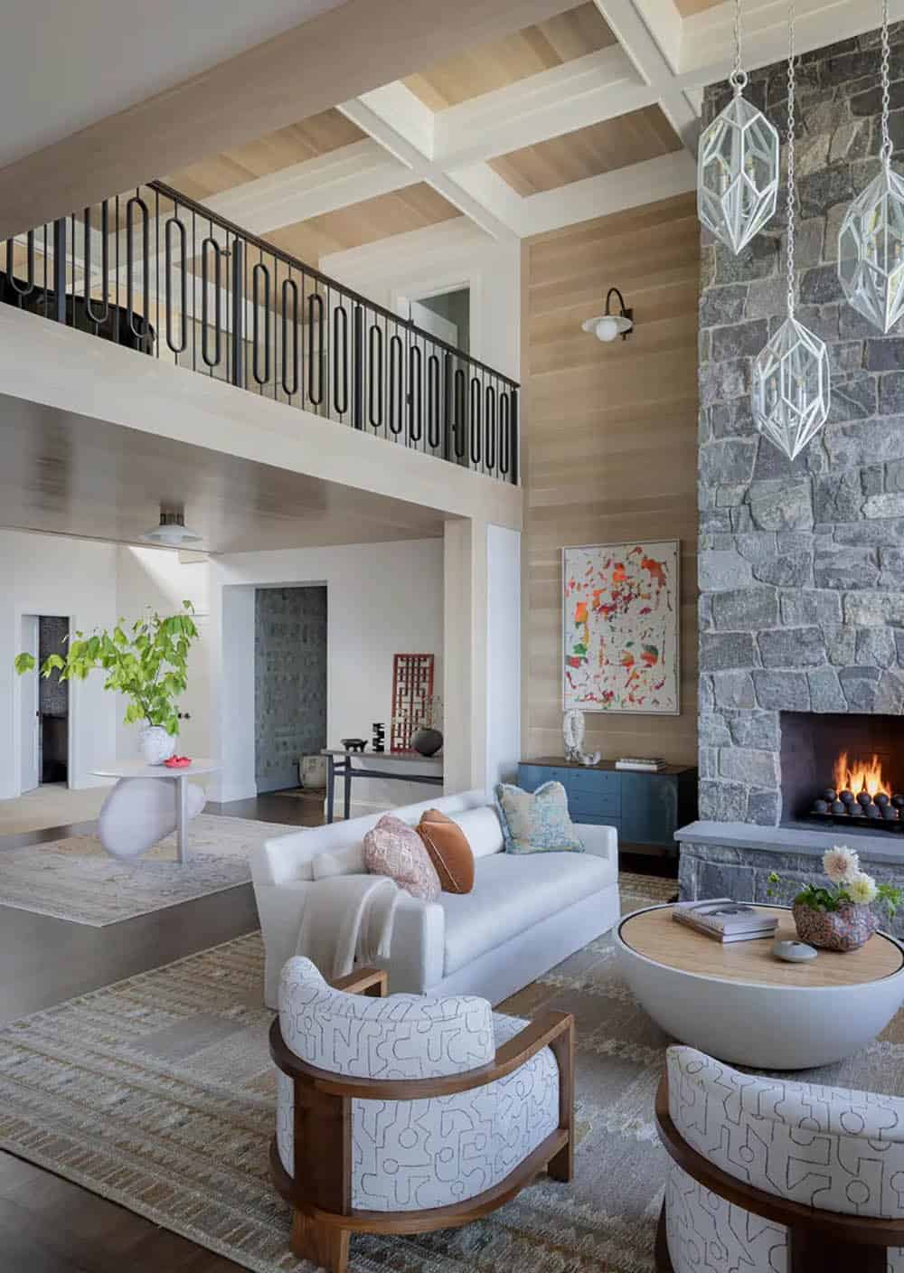 Two-story living room with iron-railed loft and stone fireplace