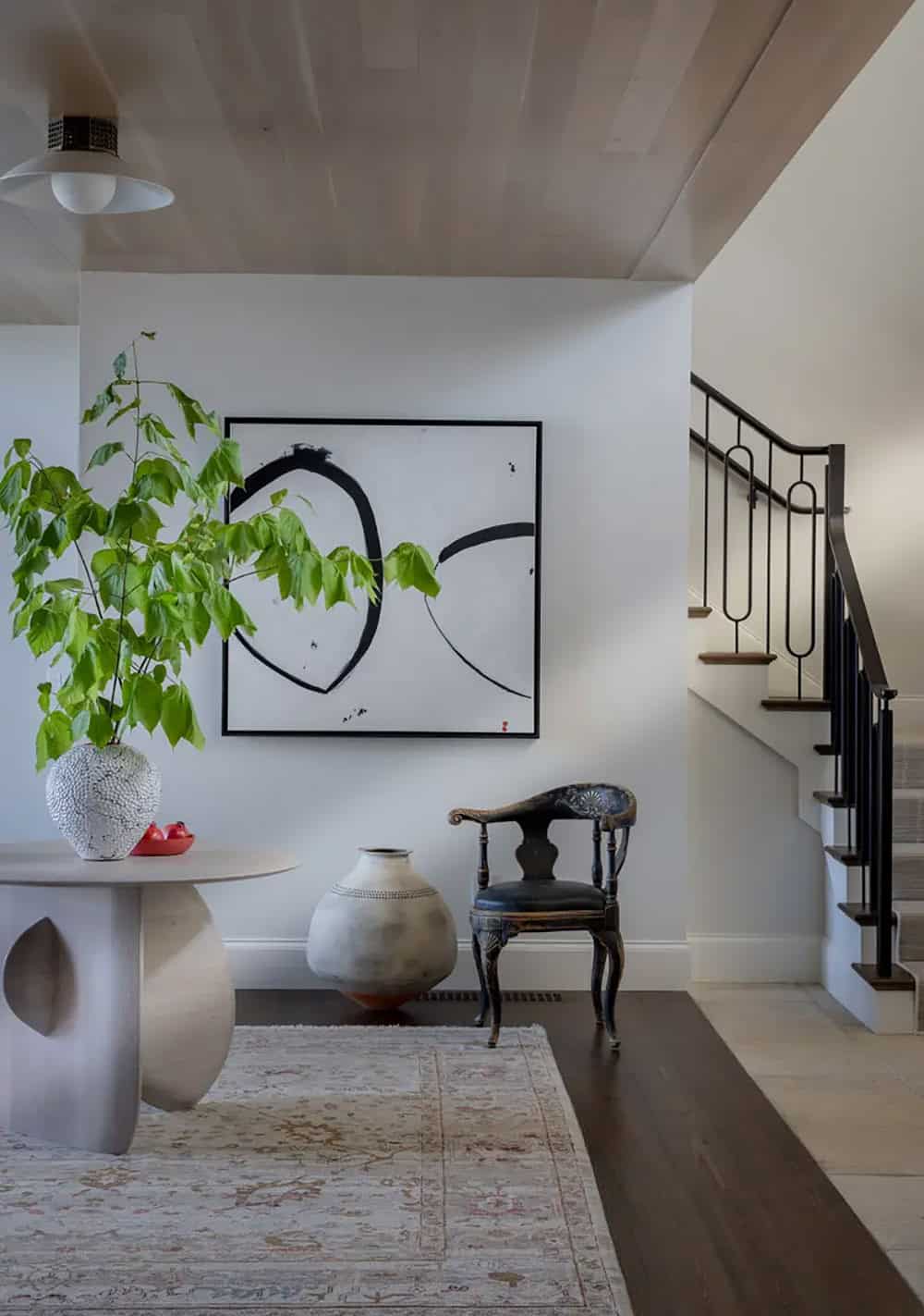 Entryway with sculptural white table, potted plant, and abstract art