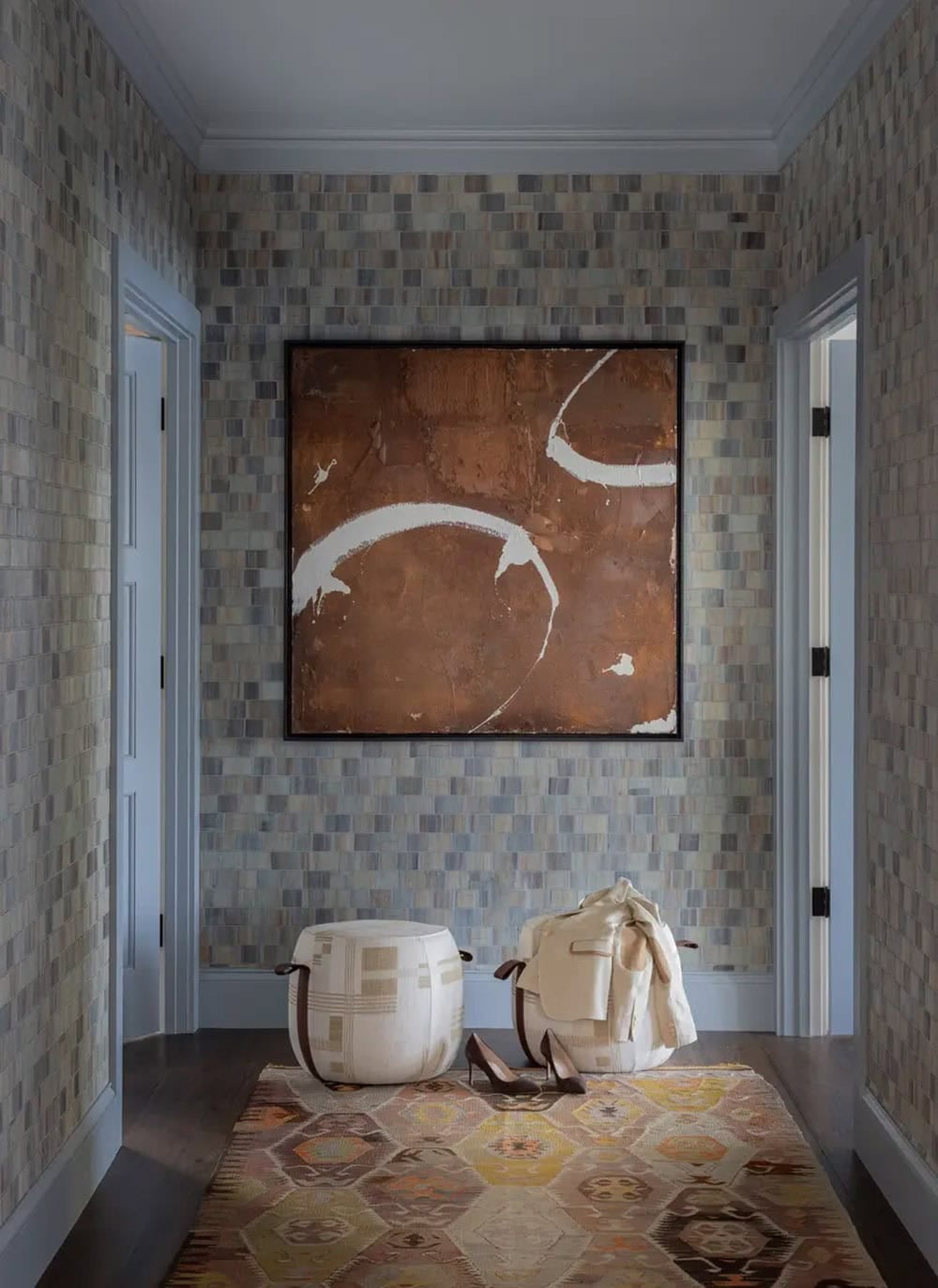 Textured tile hallway with a bronze abstract painting and poufs