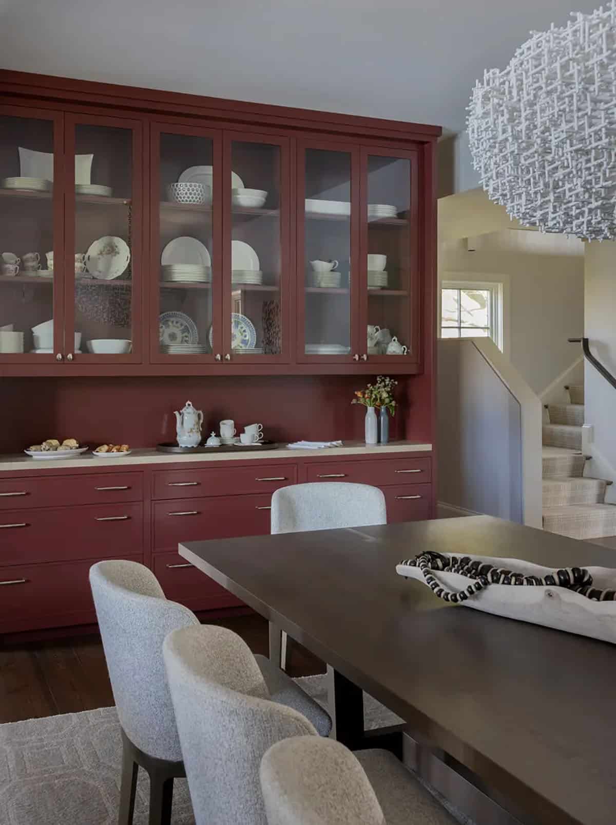 Dining room with burgundy glass-front hutch and woven pendant light