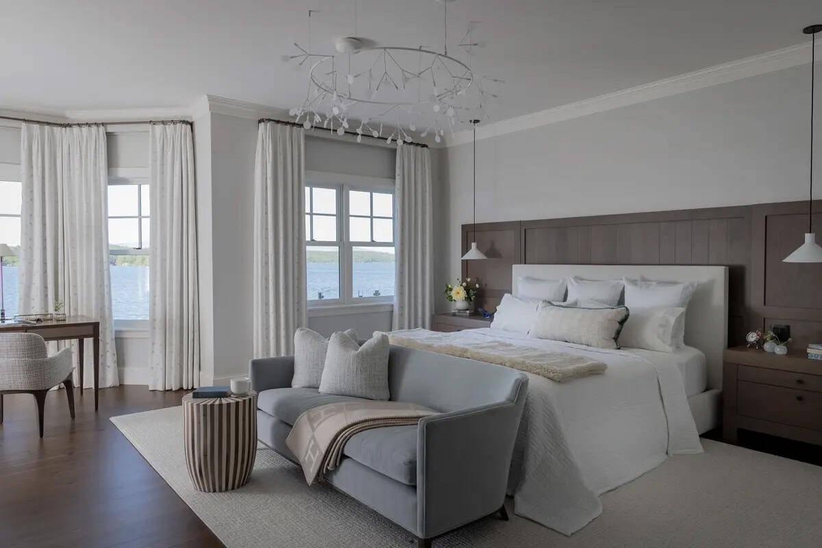 Primary bedroom with wood headboard wall and lake-view windows