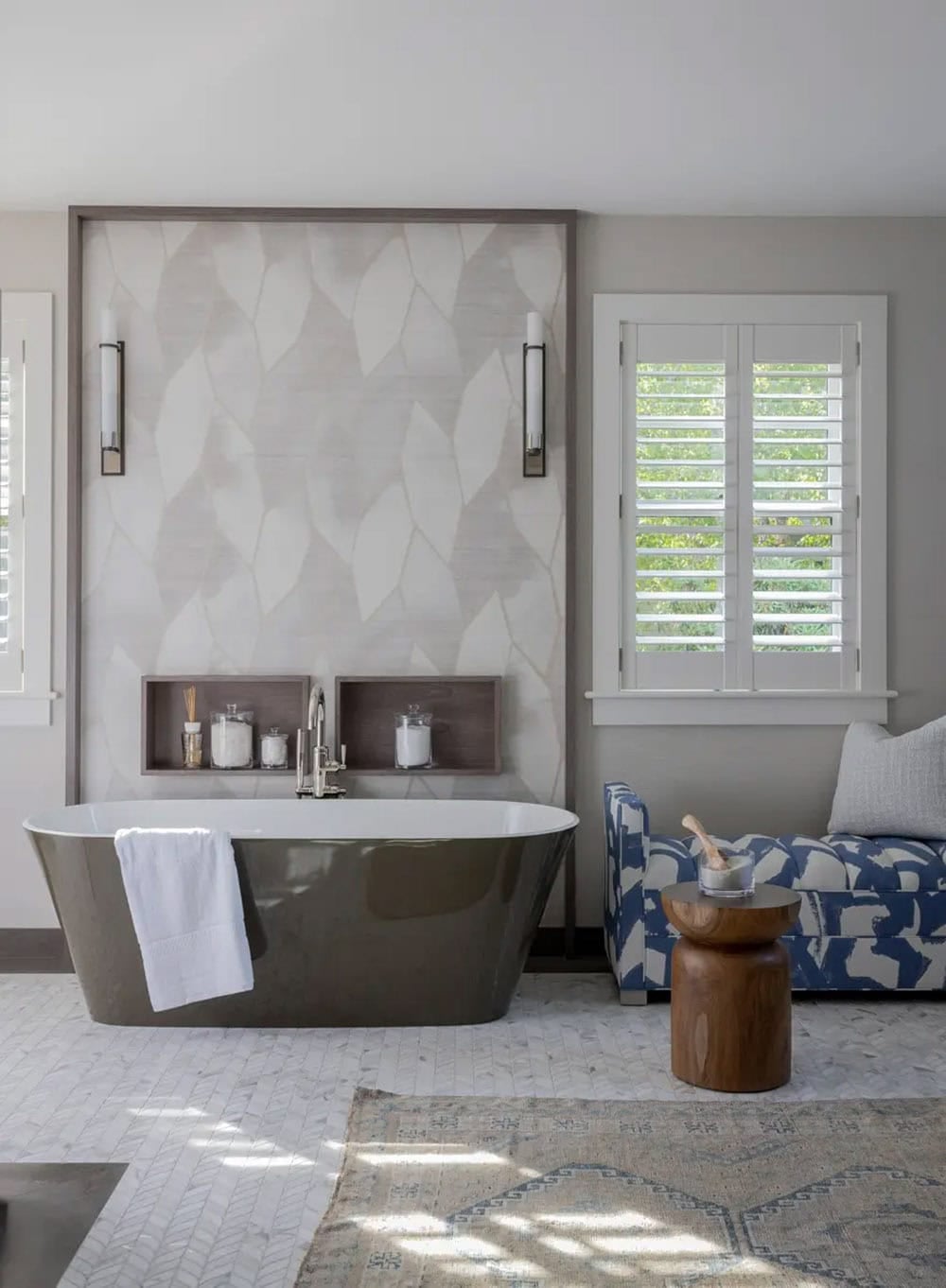 Freestanding olive tub against a patterned wall with wall sconces