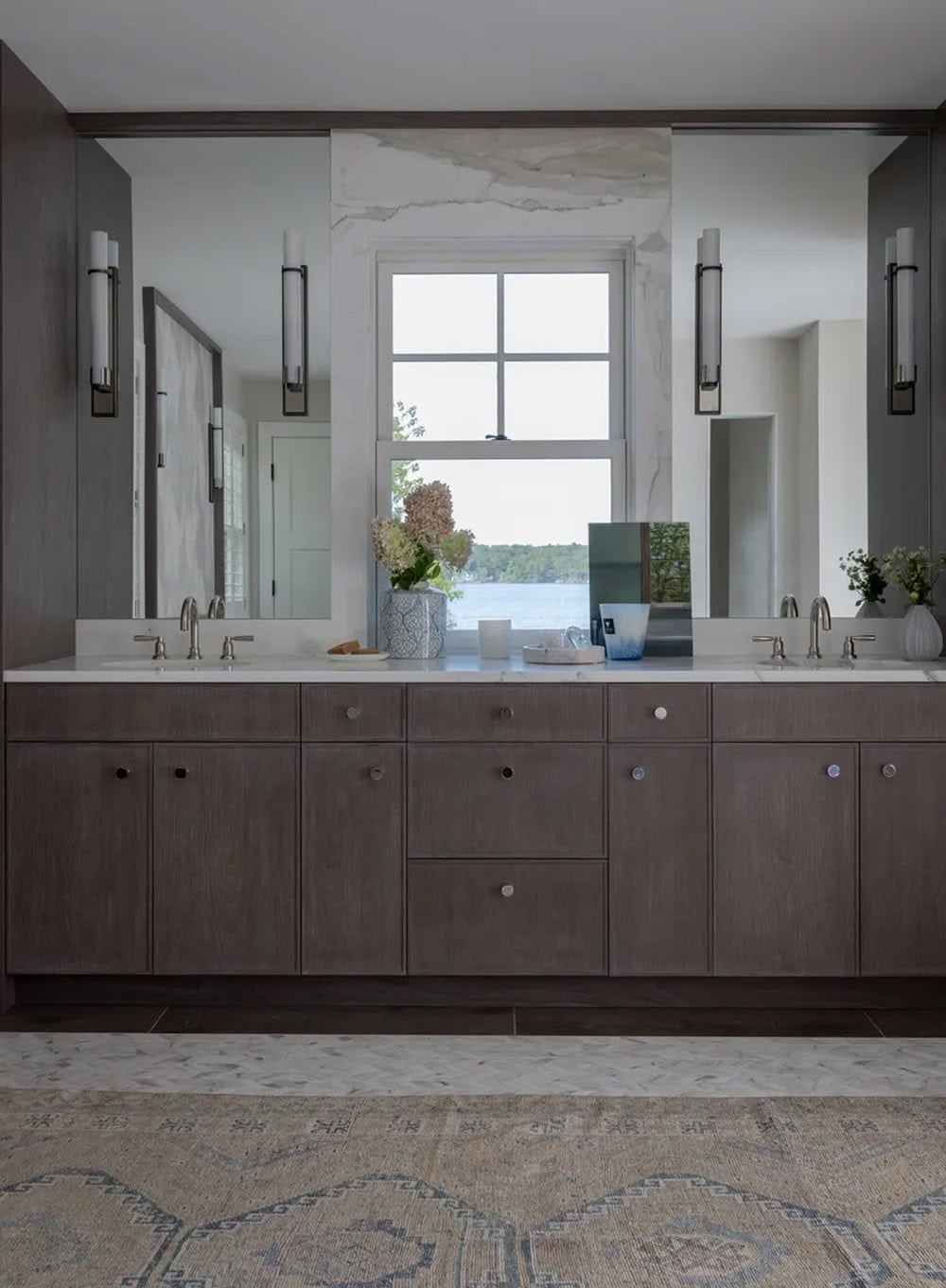 Double vanity mirror reflecting a lake view through the window