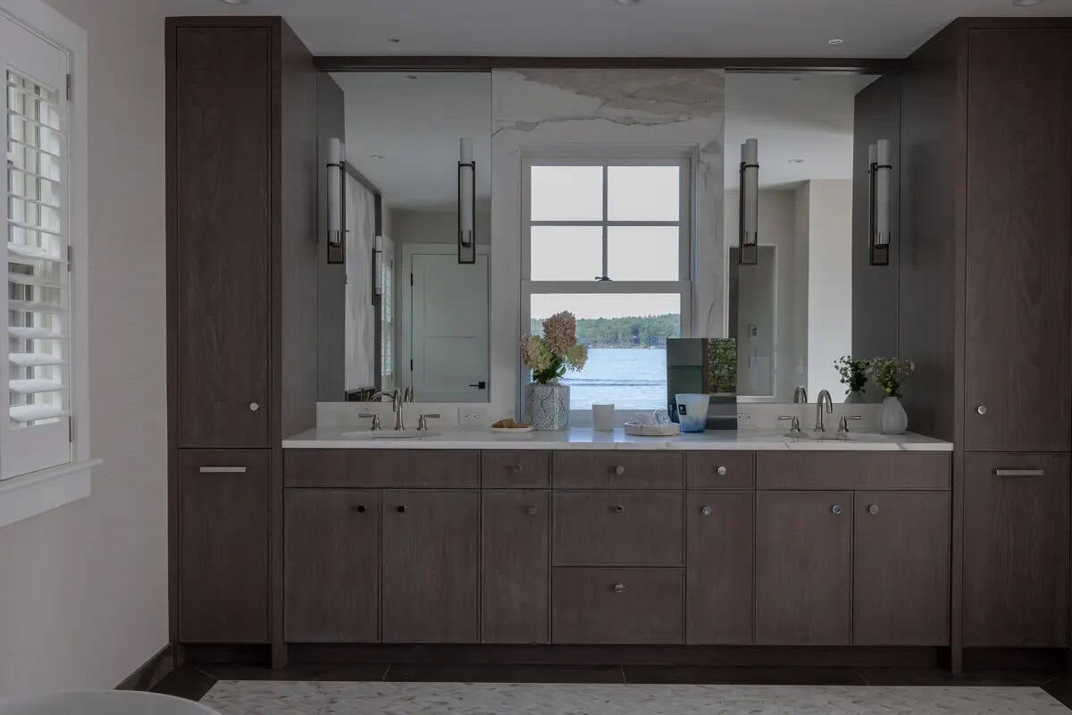 Dark wood double vanity with marble backsplash framing the window