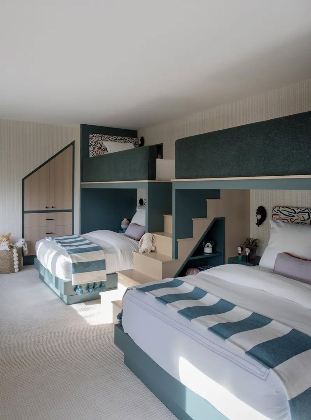 Kids' bunk room with built-in stairs and teal-trimmed sleeping nooks