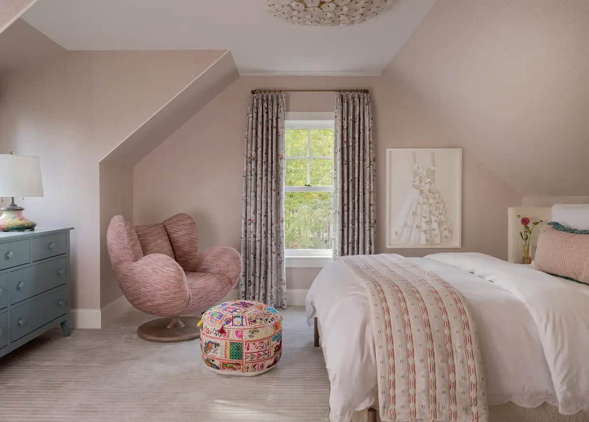 Pink bedroom with a swivel chair and floral curtains by the window