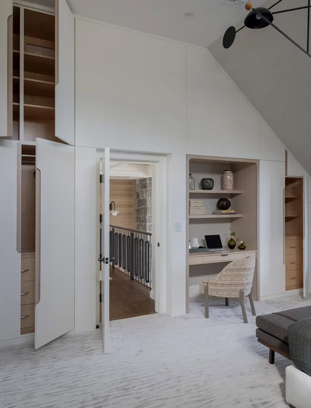Open closet doors revealing built-in desk nook under sloped ceiling
