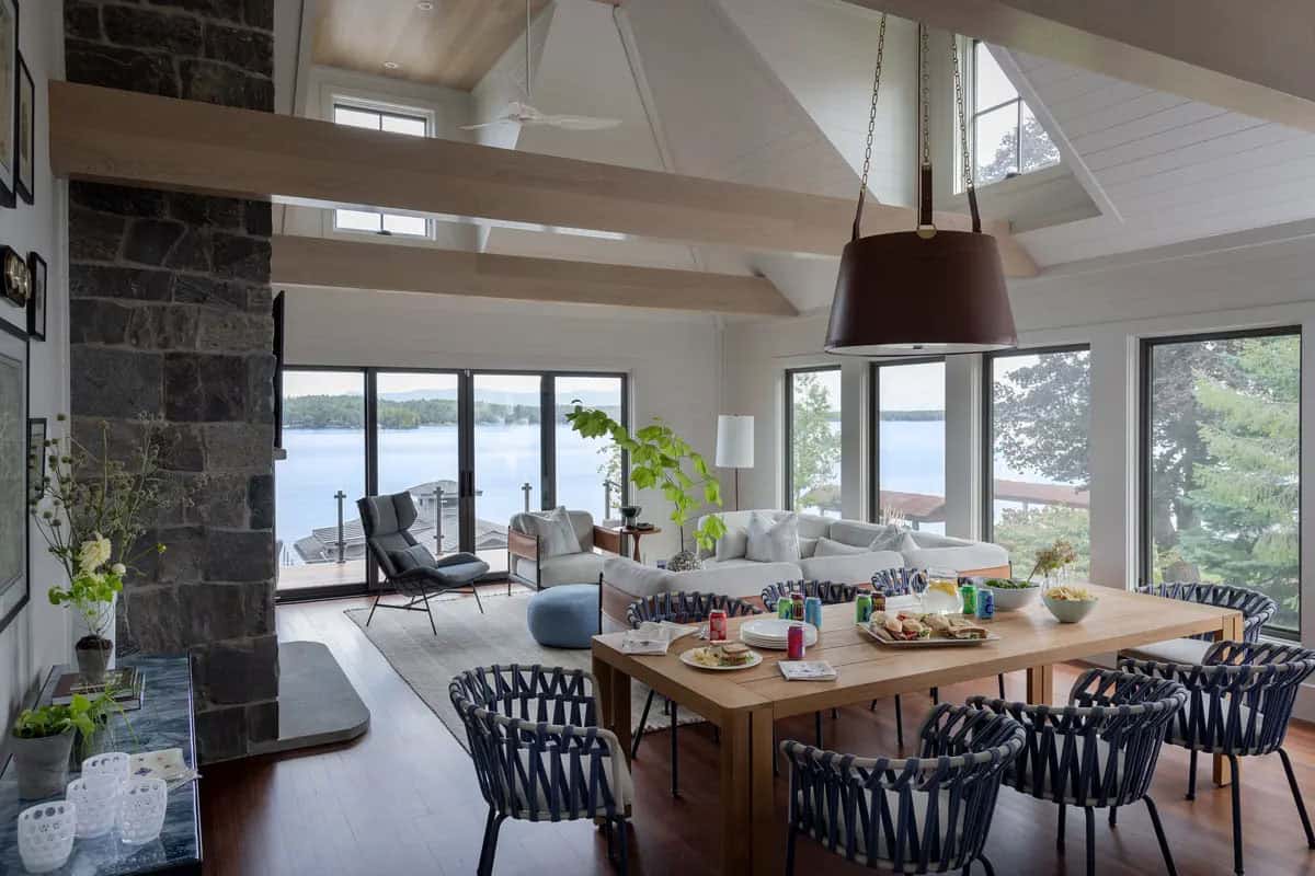 Vaulted great room with stone chimney and dining table by the lake