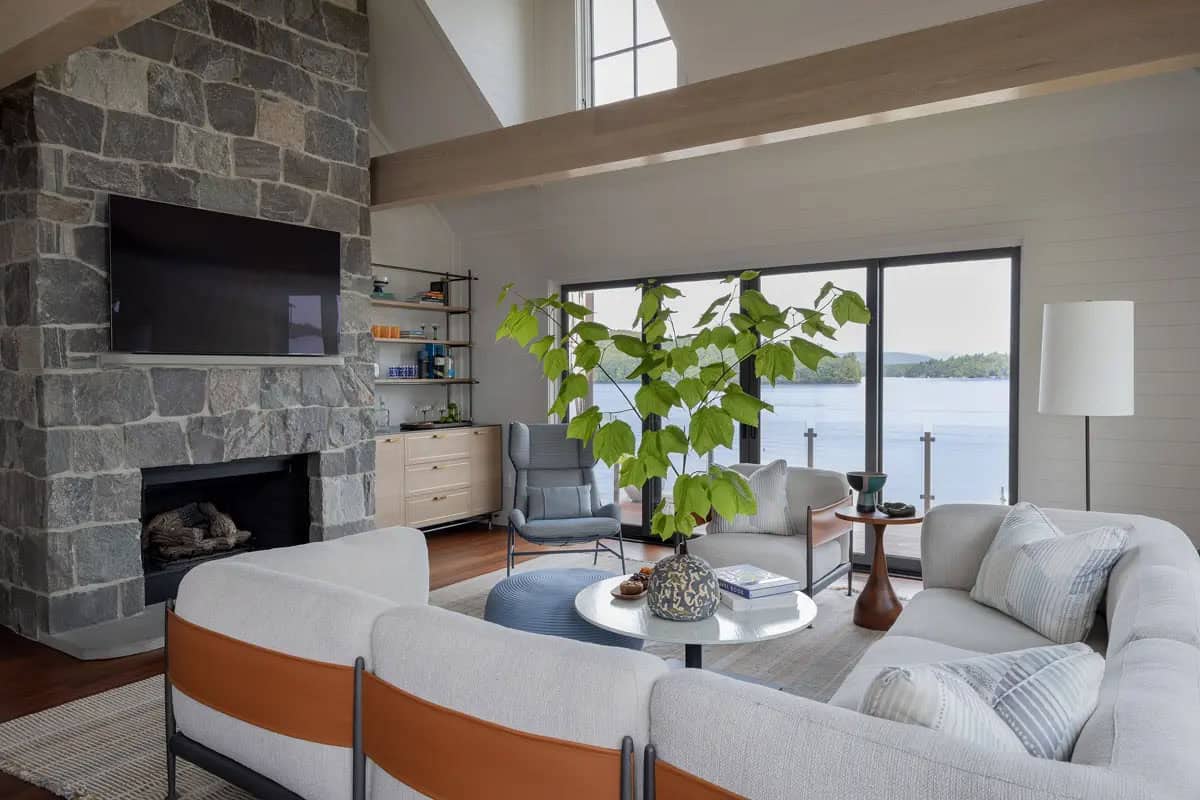 Living room with stone fireplace and mounted TV facing the lake