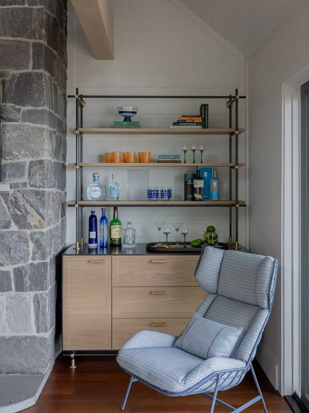 Bar nook with open shelving beside a stone chimney
