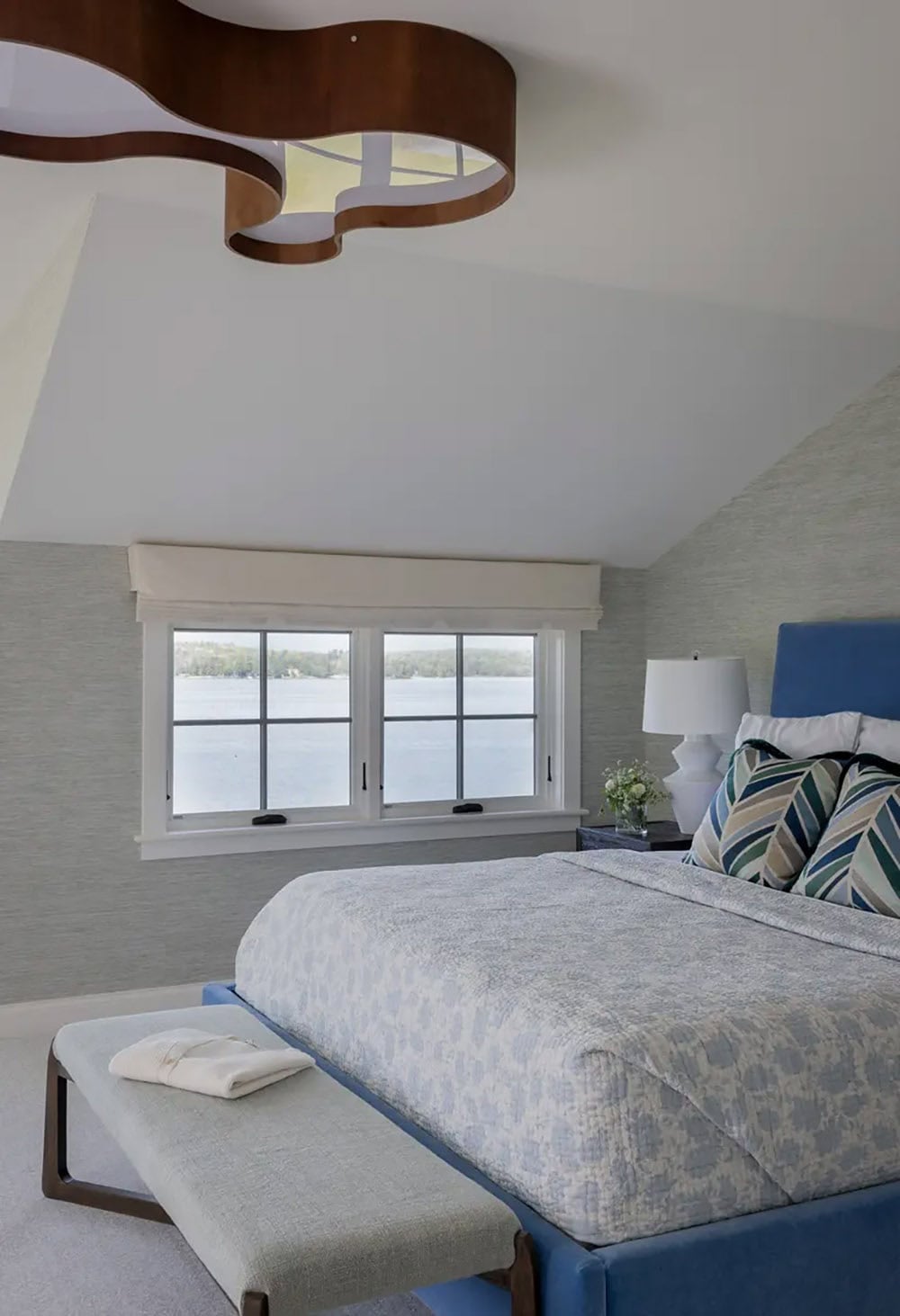 Bedroom with sculptural wood pendant light and lake view window