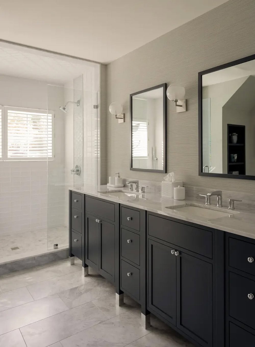 Bathroom with black vanity, marble counters, and glass shower