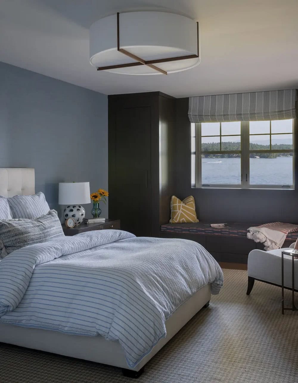 Bedroom with dark wardrobe, window seat, and lake view