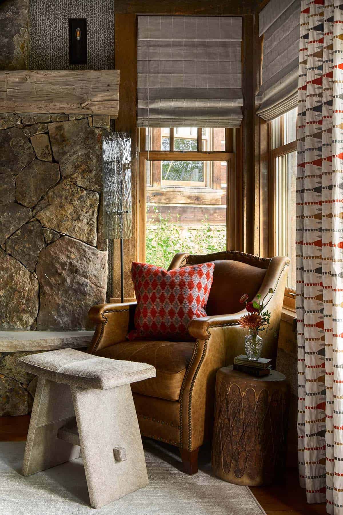 Reading chair in leather with stone fireplace and patterned curtains