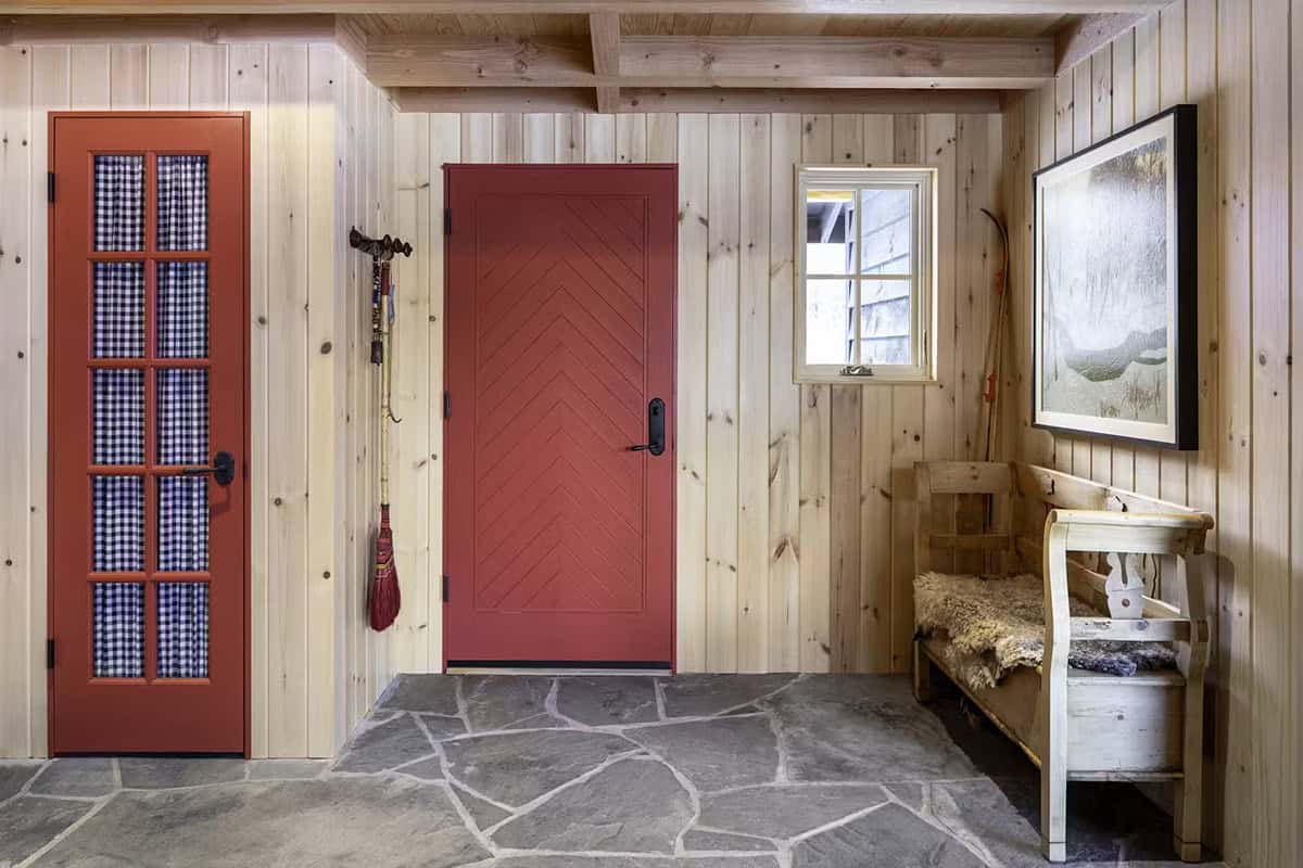 Entryway with red door, wood paneling, and stone floor