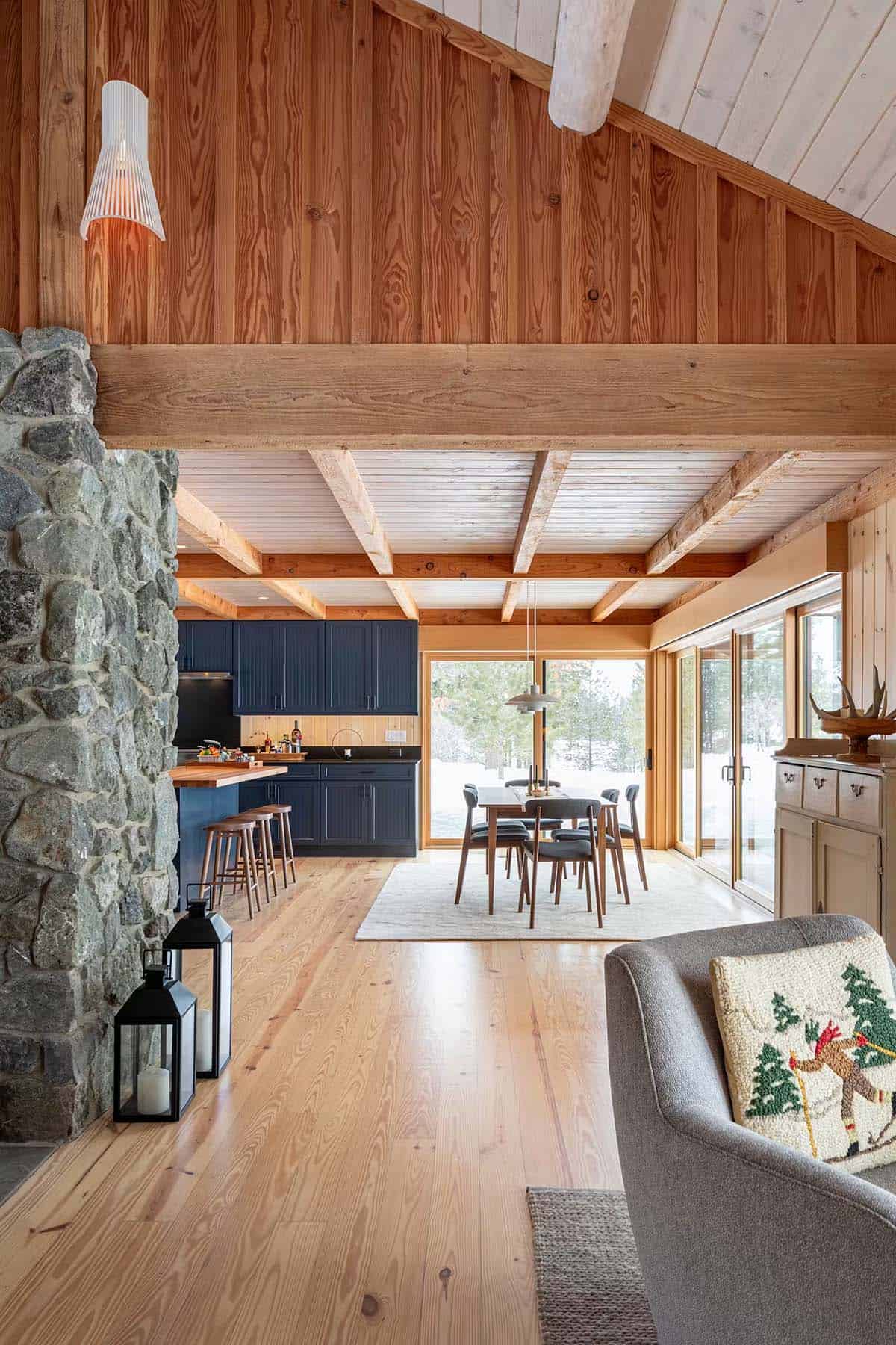 Open living, dining, and kitchen area with stone fireplace and beamed ceiling