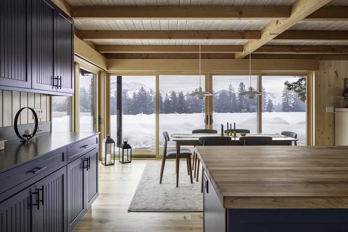 Kitchen and dining area with navy cabinets and floor-to-ceiling windows overlooking snow